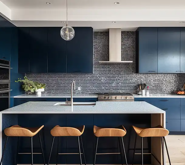 Kuchnia z ciemnoniebieskimi szafkami, wyspą kuchenną i stołkami barowymi w minimalistycznym wnętrzu.